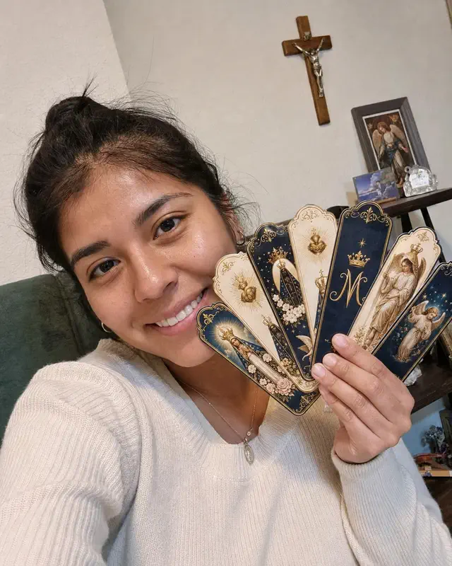 Young person showing several Catholic bookmarks